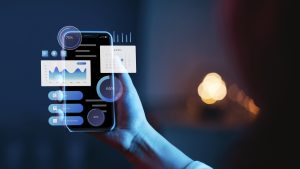 Eine Person hält ein Smartphone, auf dem holografische Benutzeroberflächenelemente wie Diagramme, Kalender und Fortschrittsanzeigen angezeigt werden – symbolisch für moderne App-Entwicklung und digitale Benutzererfahrung.