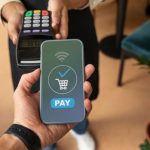 Eine Person hält ein Smartphone mit einer digitalen Bezahlbestätigung über ein kontaktloses Terminal – modernes Beispiel dafür, wie Karten virtuell für schnelle und sichere Zahlungen verwendet werden.