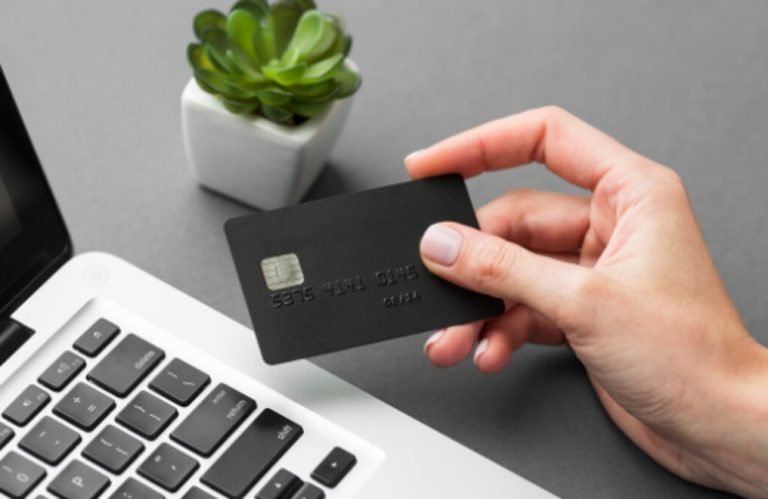 Eine Hand hält eine schwarze Kreditkarte über der Tastatur eines Laptops, bereit für eine Online-Transaktion. Die Szene symbolisiert modernes digitales Einkaufen und die Bedeutung von Kreditlimits bei der Verwaltung persönlicher Finanzen.