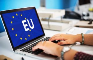Person arbeitet am Laptop mit EU-Flagge auf dem Bildschirm, Symbol für Finanzwesen und europäische Bankenintegration.