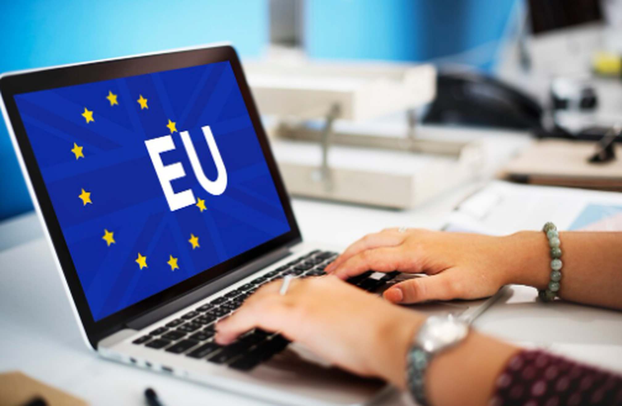 Person arbeitet am Laptop mit EU-Flagge auf dem Bildschirm, Symbol für Finanzwesen und europäische Bankenintegration.