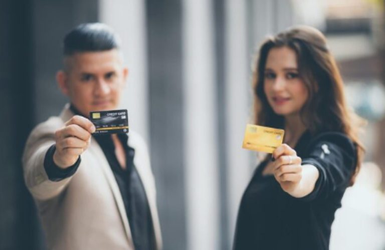 Mann und Frau halten jeweils eine Kreditkarte in der Hand, Symbol für den Einsatz von revolvierenden und Ratenkreditkarten im modernen Finanzwesen.